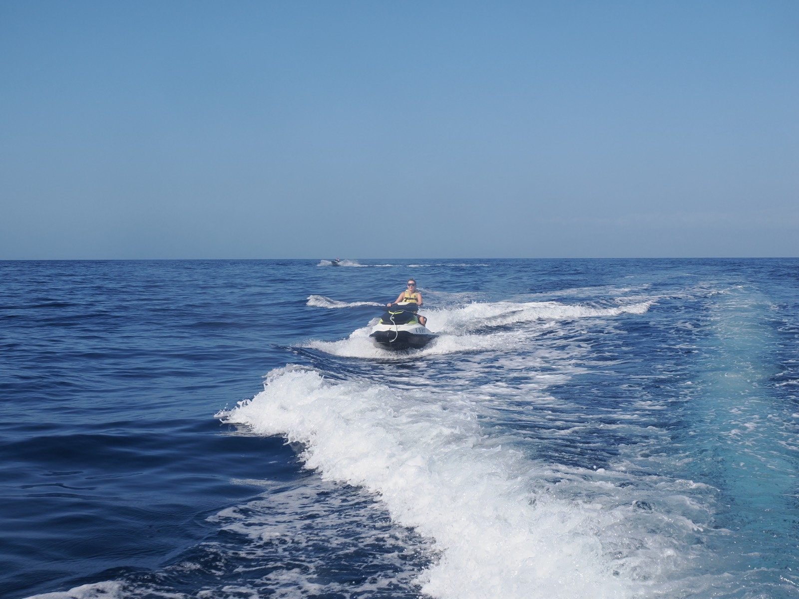 Jet ski at speed on open water off Costa Adeje, spray trailing behind